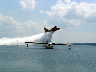 Dramatic photo of C-FNJF on the water at Biscarosse, France with a visiting Canadair CL-215 dropping its water load in the background Photo: Bernard Servieres